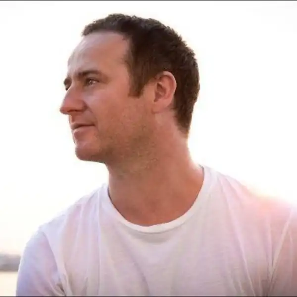 Man in a white T-shirt looking to the left against a bright background
